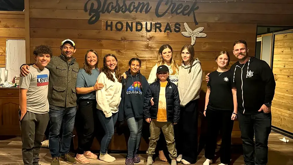 The team standing together under the Blossom Creek sign at the mill in Honduras