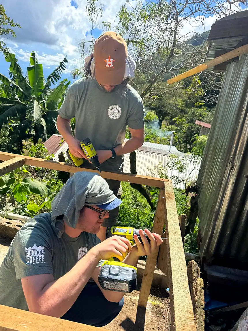 Two of our team drilling and fixing timber to frame a new drying bed at the farm