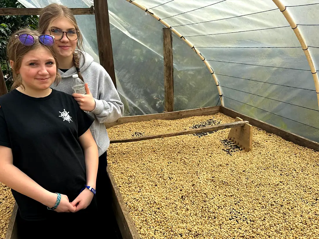 Two young visitors standing beside the raised drying beds inside the greenhouse